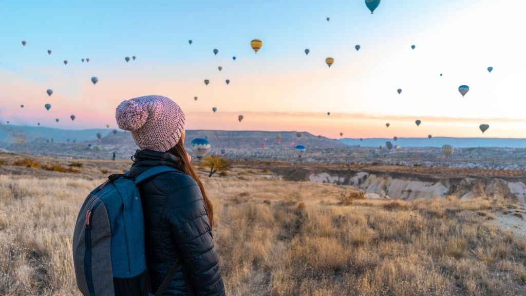 Femme regardant à l'horizon un vol de mongolfières