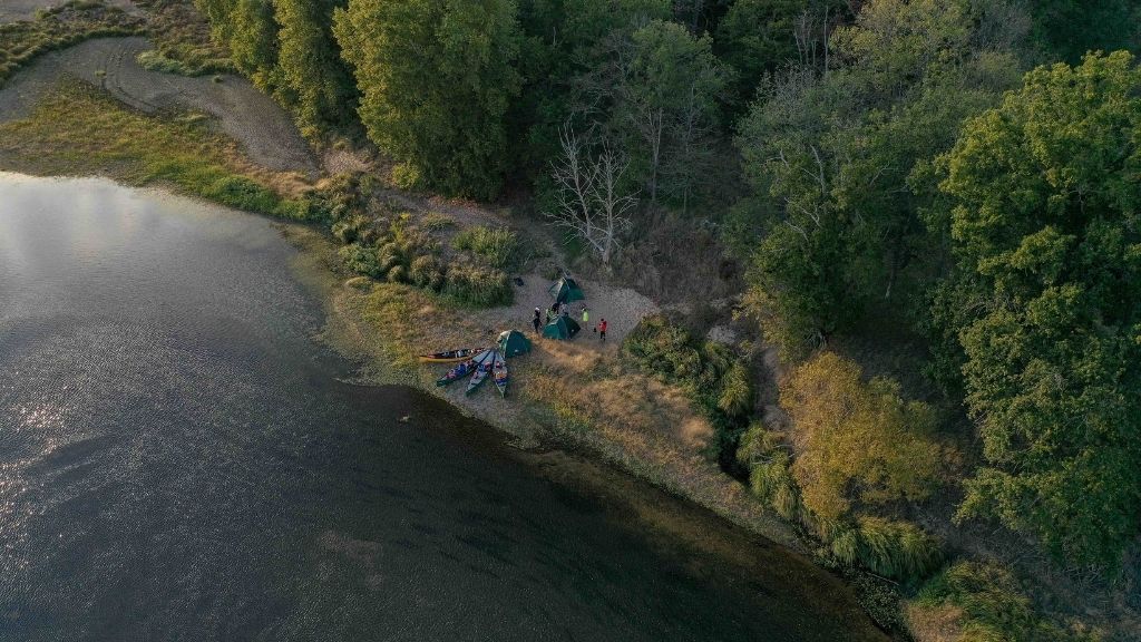 Bivouac au bord de la rivière avec canoë vu du ciel