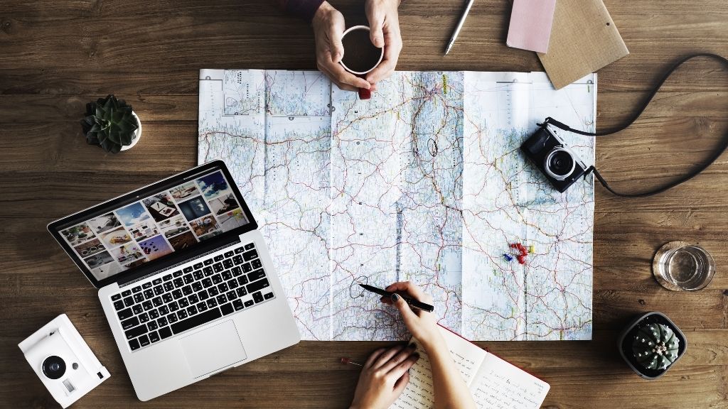 Planification de voyage avec carte, ordinateur appareil photo et un bon café